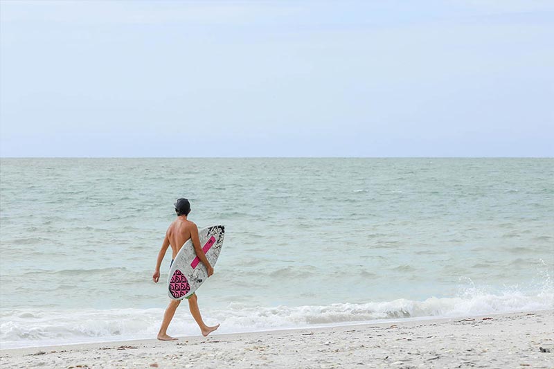 a man with a surfboard in his hand at the beach
